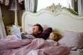 Cute adorable little toddler girl and father watching cartoons on laptop in bed. Tired baby child and man with tablet Royalty Free Stock Photo