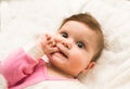 Cute adorable 8 months baby girl sucking finger as getting first tooth. Closeup of adorable little girl on the white bed. Oral Royalty Free Stock Photo