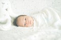 Cute adorable newborn baby boy wrapped or swaddle in a blanket, sleeping and sometime both eyes open in kids bed Royalty Free Stock Photo