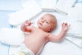 Cute adorable newborn baby on changing table with diapers. Cute little girl or boy looking at the camera. Dry and Royalty Free Stock Photo