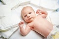 Cute adorable newborn baby on changing table with diapers. Cute little girl or boy looking at the camera. Dry and Royalty Free Stock Photo