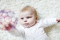 Cute adorable newborn baby playing with colorful ball toy on white background. New born child, little girl looking at Royalty Free Stock Photo