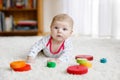 Cute adorable newborn baby playing with colorful wooden rattle toy ball on white background. New born child, little girl Royalty Free Stock Photo