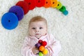 Cute adorable newborn baby playing with colorful wooden rattle toy ball on white background. New born child, little girl Royalty Free Stock Photo