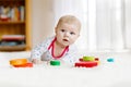 Cute adorable newborn baby playing with colorful wooden rattle toy ball on white background. New born child, little girl Royalty Free Stock Photo