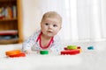 Cute adorable newborn baby playing with colorful wooden rattle toy ball on white background. New born child, little girl Royalty Free Stock Photo