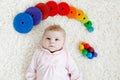 Cute adorable newborn baby playing with colorful wooden rattle toy ball on white background. New born child, little girl Royalty Free Stock Photo