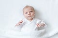 Cute adorable newborn baby in white bed and wrapped in blanket. New born child, little girl looking surprised at the Royalty Free Stock Photo