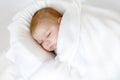 Cute adorable newborn baby wrapped in white blanket, sleeping in kids bed or cocoon. Closeup of peaceful child, little Royalty Free Stock Photo