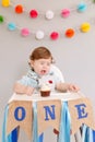 Cute adorable sad upset Caucasian baby boy celebrating first birthday at home. Pensive child kid toddler sitting in high chair Royalty Free Stock Photo