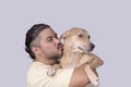 Cute and adorable scene of a man kissing his spoiled mid-sized adult dog he is carrying on his shoulders. Isolated on a white