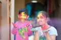 Cute adorable siblings playing with colours during holi festival of colors Indian asian caucasian creative portrait