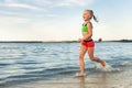 Cute adorable sporty caucasian blond school girl enjoy having fun running water by lake or sea sand beach splashing Royalty Free Stock Photo