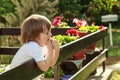 Cute adorable toddler boy with down sydrome stand leande on fance looking away while  sucking hand in mouth Royalty Free Stock Photo