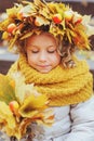 Cute adorable toddler girl portrait with bouquet of autumn leaves and wreath walking outdoor in park Royalty Free Stock Photo