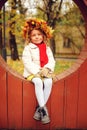 Cute adorable toddler girl portrait with bouquet of autumn leaves and wreath walking outdoor in park Royalty Free Stock Photo