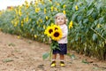 Cute adorable toddler girl on sunflower field with yellow flowers. Beautiful baby child with blond hairs. Happy healthy Royalty Free Stock Photo