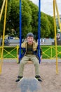 Cute adorable toddler girl swinging on outdoor playground. Happy smiling baby child sitting in chain swing Royalty Free Stock Photo