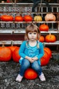 cute adorable white Caucasian red-haired little girl child sitting on large pumpkin on farm Royalty Free Stock Photo
