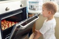 Cute adroable little caucasian blond 3-4 years boy enjoy have fun looking in open oven door checking baking sweet Royalty Free Stock Photo