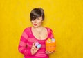 Pretty adult chubby woman with short hair holding colorful holiday eggs and a easter basket on yellow solid studio background