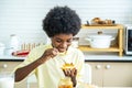 Cute african american boy spreading jam on bread and eating in kitchen, student enjoys breakfast or snacks of toast with jam