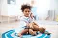 Cute African American child imagining herself as doctor while playing with stethoscope and toy bunny Royalty Free Stock Photo