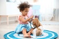 Cute African American child imagining herself as doctor while playing with stethoscope and toy bunny