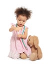 Cute African American child imagining herself as doctor while playing with stethoscope and toy bunny on white