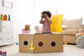 Cute African American child playing with cardboard ship and binoculars