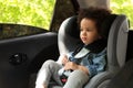 Cute African-American child sitting in safety seat inside car