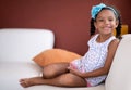 Cute african american girl sitting on a couch and smiling Royalty Free Stock Photo