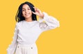 Cute african american girl wearing casual white tshirt smiling and confident gesturing with hand doing small size sign with Royalty Free Stock Photo