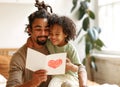 Cute african american little boy son giving his father handmade greeting postcard on Fathers Day Royalty Free Stock Photo