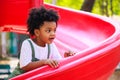 Cute African American little kid boy having fun while playing on the playground in the daytime in summer. Outdoor activity. Royalty Free Stock Photo