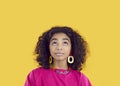 Cute african american preteen girl thinking, coming up with idea or fantasizing on yellow background