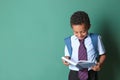 Cute African-American schoolboy reading book on color background Royalty Free Stock Photo