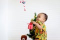 Cute African baby kid colorful dress looking at hanging ornament decorative items with Christmas tree as blurred background in Royalty Free Stock Photo