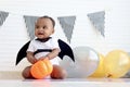 Cute African baby kid dressing up vampire fancy Halloween costume with black bat wings, cheerful little cute child holds Halloween Royalty Free Stock Photo