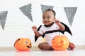 Cute African baby kid dressing up vampire fancy Halloween costume with black bat wings, cheerful little cute child holds Halloween Royalty Free Stock Photo