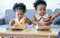 Cute African daughter eating pizza at home. Children kids enjoy and having fun with tasty lunch meal together. Parent help little Royalty Free Stock Photo