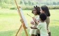 Cute African family, daughter, son and mom have fun painting coloring watercolor on canvas in green park on summer. Little Royalty Free Stock Photo