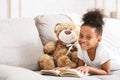 Cute afro baby girl playing with teddy bear, reading book Royalty Free Stock Photo