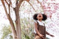 A cute Afro girls under flowering tree in park.