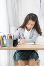 Cute Asia girl writing something in paper with colour pencils Royalty Free Stock Photo