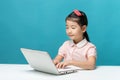 Cute asia little girl who enjoy the laptop computer on blue back Royalty Free Stock Photo