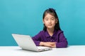 Cute asia little girl who enjoy the laptop computer on blue back Royalty Free Stock Photo