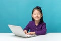 Cute asia little girl who enjoy the laptop computer on blue background Royalty Free Stock Photo