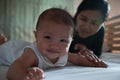 Cute asian baby girl lying on the stomach in the bed and playing with mother to relax together in bedroom Royalty Free Stock Photo