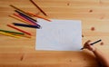 Cute Asian boy drawing happy family and home. with color pencils and white paper on wooden table, top view Royalty Free Stock Photo